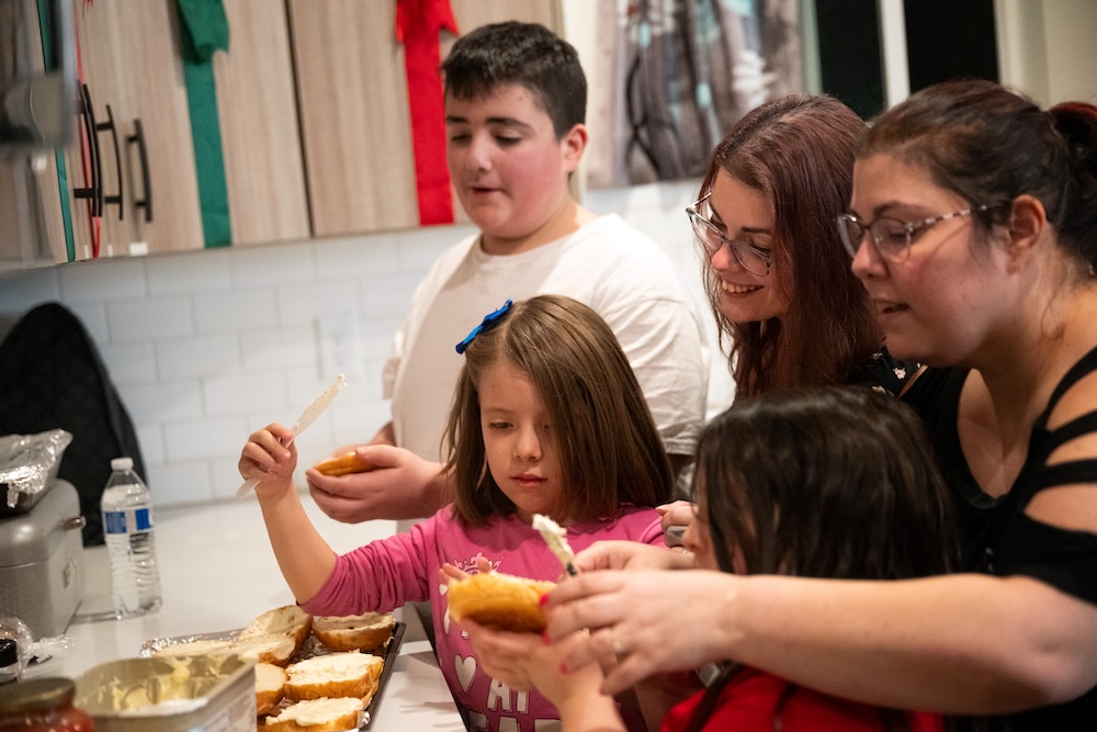 Image of a Family Preparing Food Together in a Kitchen, Spreading Toppings Onto Bread