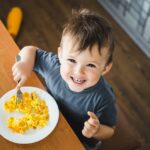 Image of a Young Boy Sitting at a Table Eating an Omelet